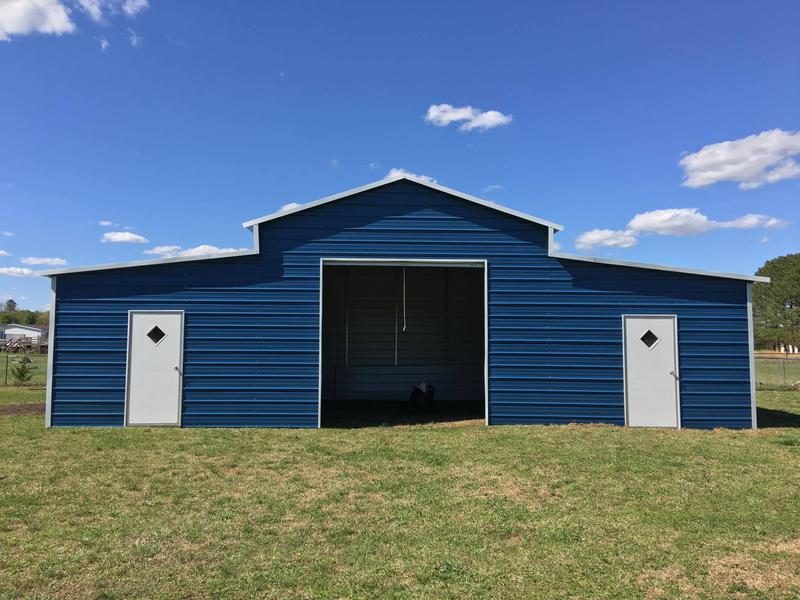Blue metal barn with a raised center section and two walk-in doors