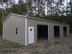 Tan three-bay metal garage with a walk-in door and window